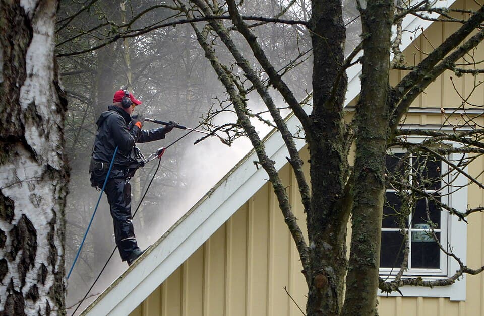 Artisan utilisant un nettoyeur haute pression sur un bâtiment