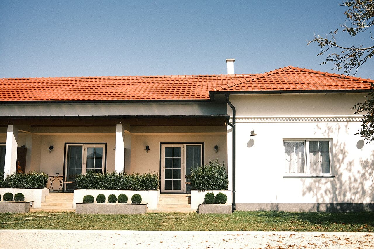 Maison à la façade nette et toiture en tuiles propre sous un ciel bleu