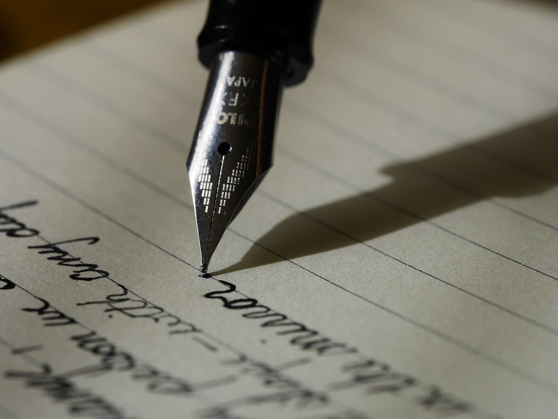 Stylo plume écrivant à l'encre sur une feuille de papier ligné